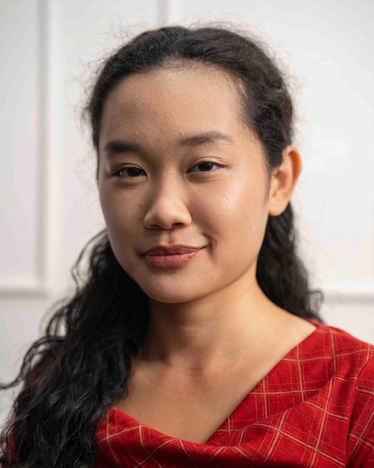 Amelia Ali warm smiling portrait in a red checked dress