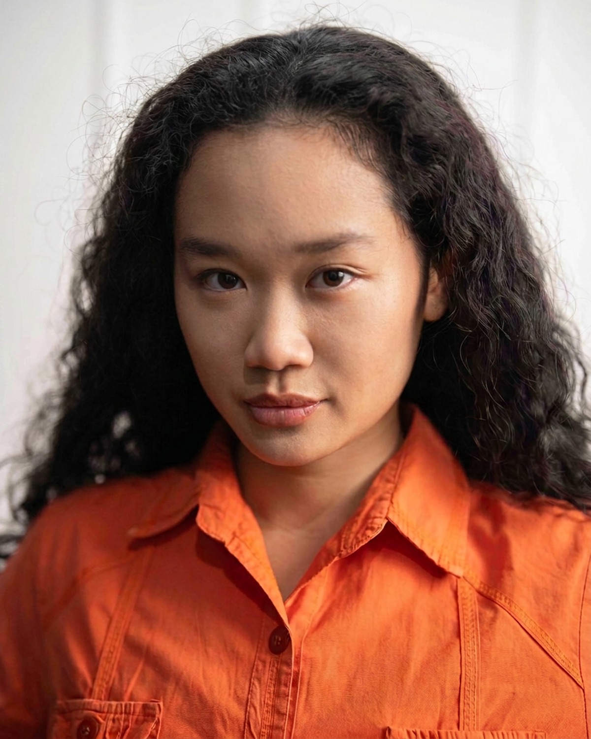 Amelia Ali studio portrait in an orange work shirt